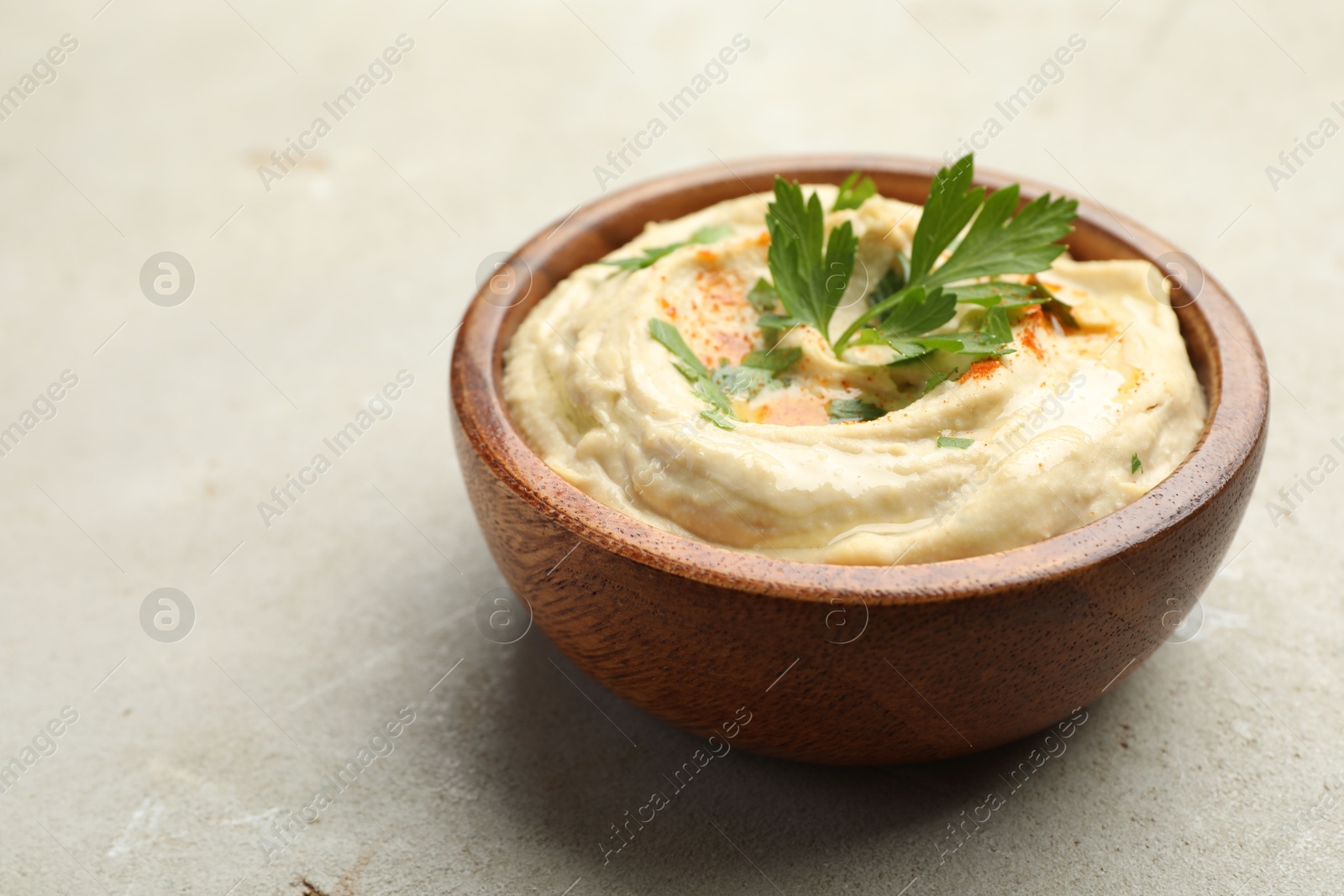 Photo of Delicious hummus with paprika and parsley in bowl on grey background, closeup