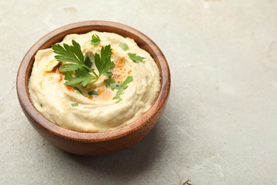 Delicious hummus with paprika and parsley in bowl on grey background, closeup. Space for text