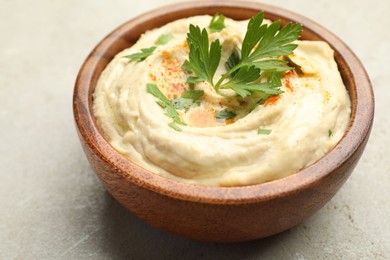 Photo of Delicious hummus with paprika and parsley in bowl on grey background, closeup