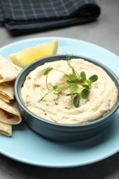 Photo of Delicious hummus in bowl, pita and lemon on table, closeup