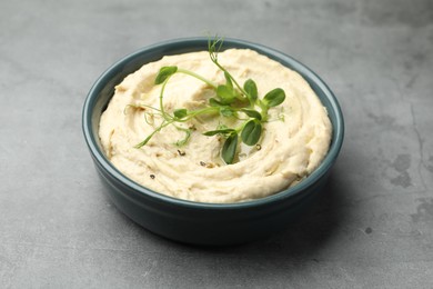 Delicious hummus in bowl on grey table, closeup