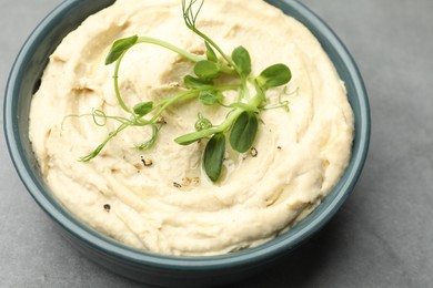 Photo of Delicious hummus in bowl on grey table, closeup