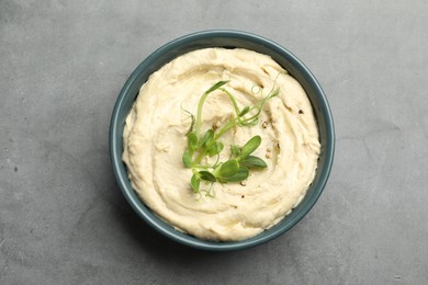 Photo of Delicious hummus in bowl and pita on grey table, top view