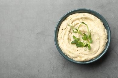 Photo of Delicious hummus in bowl and pita on grey table, top view. Space for text