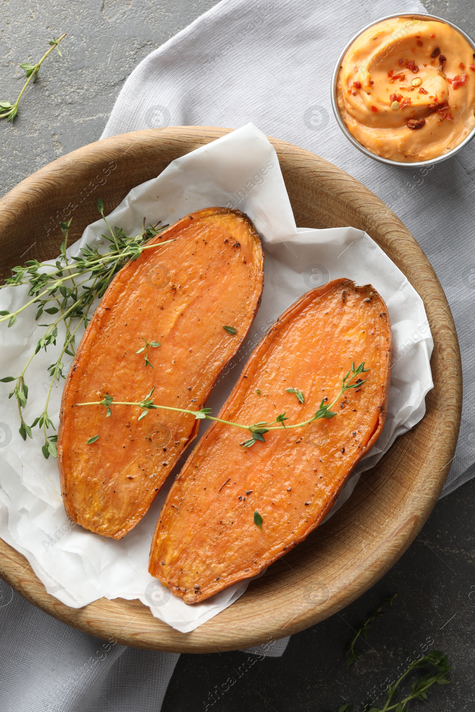 Photo of Tasty cooked sweet potato with thyme and sauce on grey table, top view