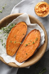 Photo of Tasty cooked sweet potato with thyme and sauce on grey table, top view