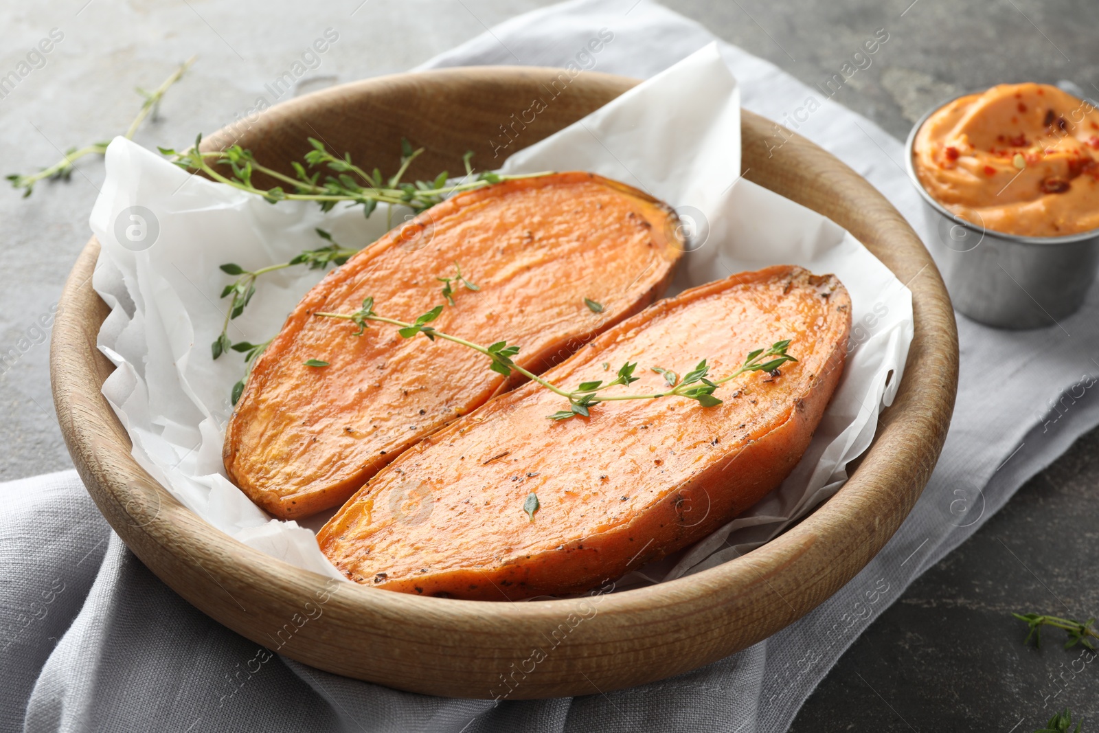 Photo of Tasty cooked sweet potato with thyme and sauce on grey table, closeup