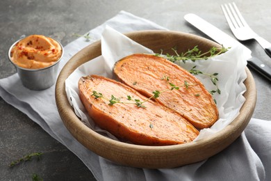 Tasty cooked sweet potato with thyme and sauce on grey table, closeup