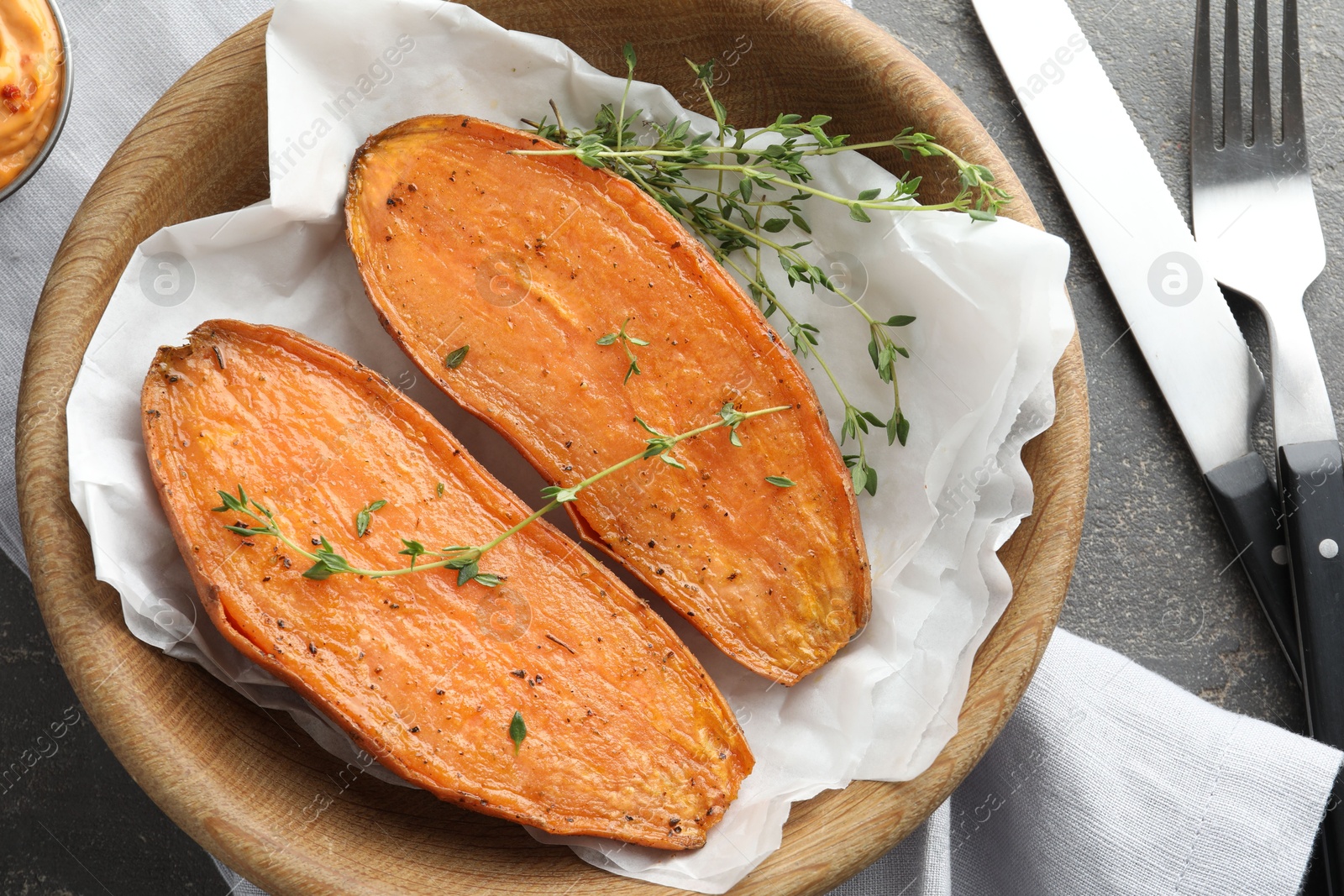 Photo of Tasty cooked sweet potato served with thyme on grey table, top view