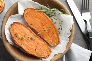 Photo of Tasty cooked sweet potato served with thyme on grey table, top view