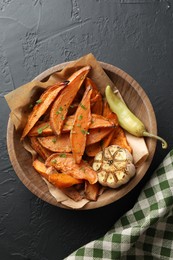 Photo of Tasty cooked sweet potatoes with garlic and pickled pepper on black table, top view