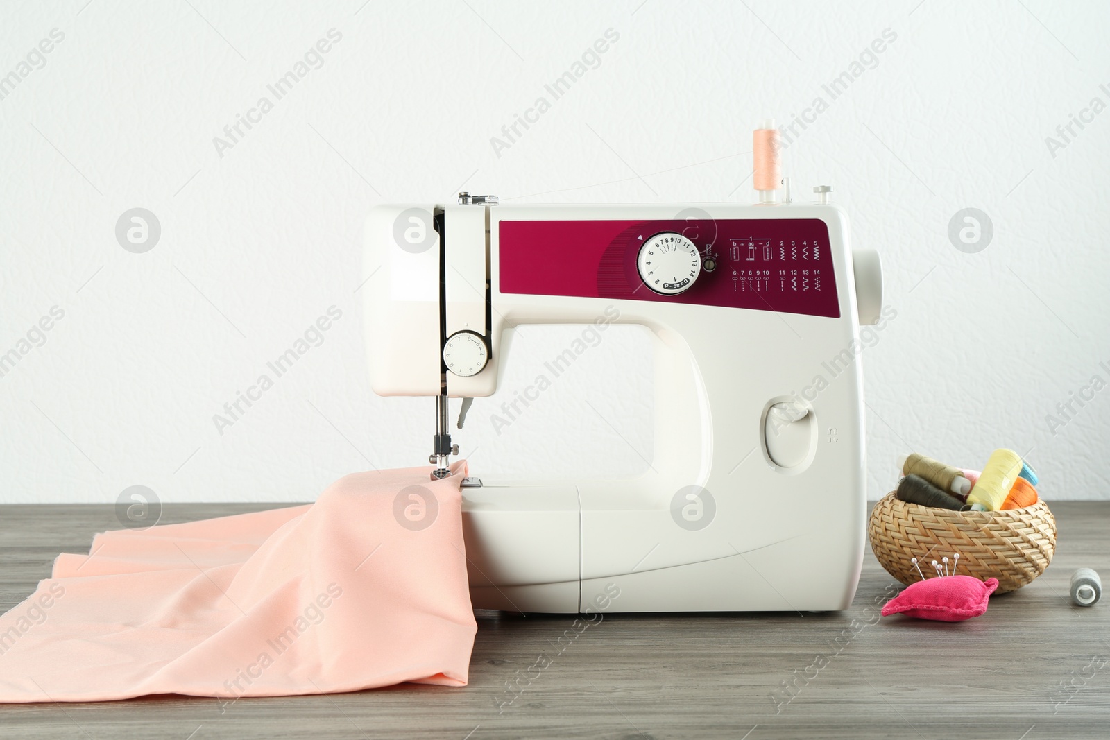 Photo of One sewing machine with fabric and tools on wooden table against white background