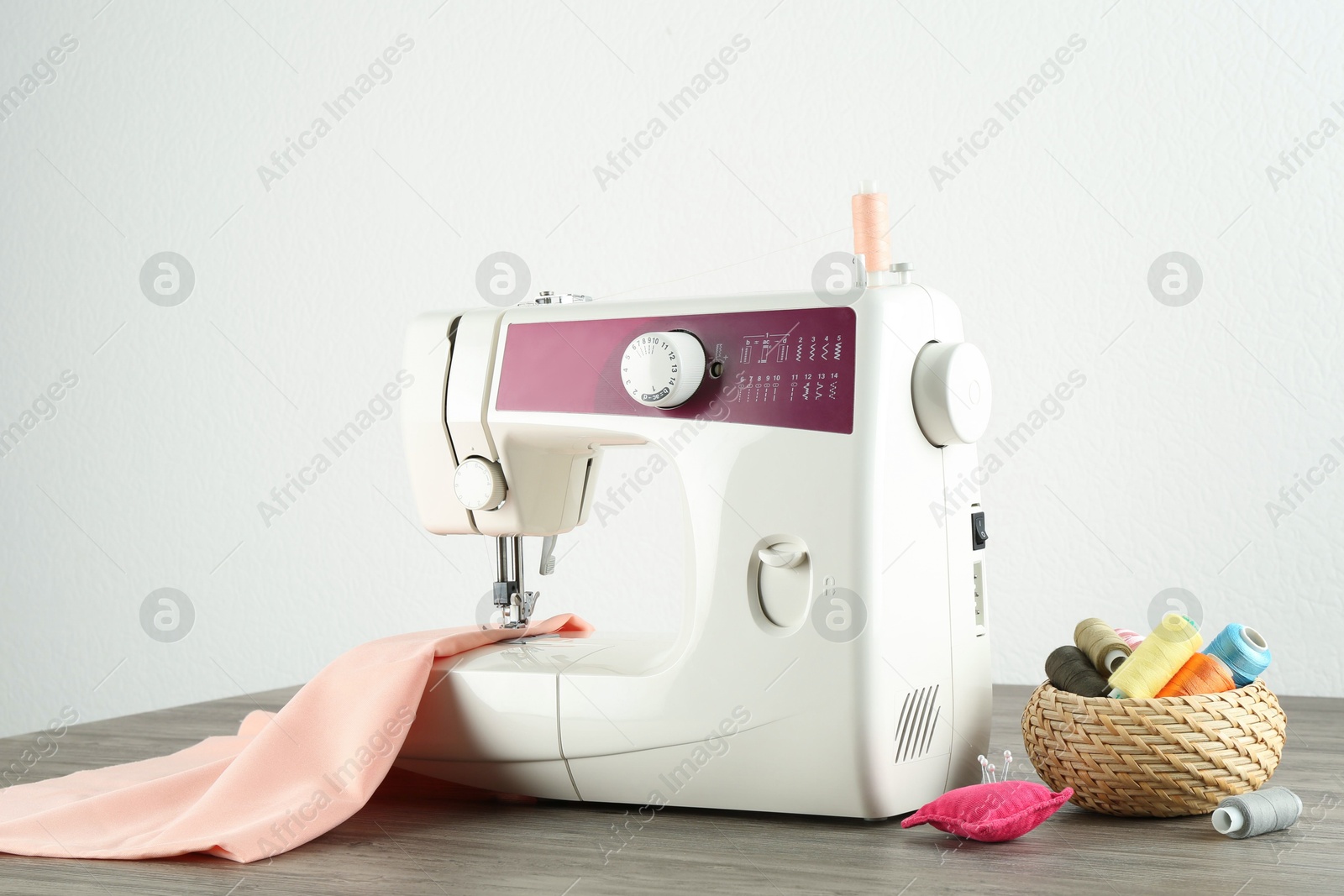 Photo of One sewing machine with fabric and tools on wooden table against white background