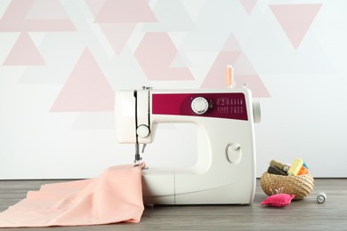 Photo of One sewing machine with fabric and tools on wooden table indoors