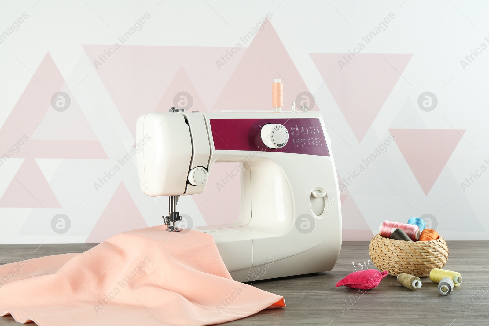 Photo of One sewing machine with fabric and tools on wooden table indoors