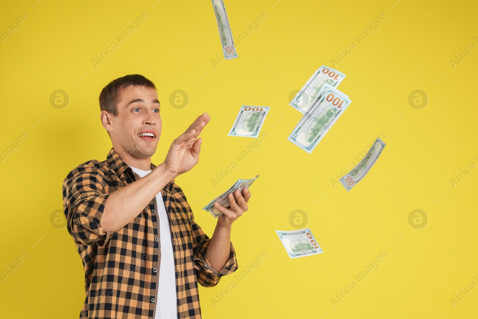 Photo of Happy man throwing money on yellow background