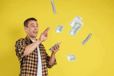 Photo of Happy man throwing money on yellow background