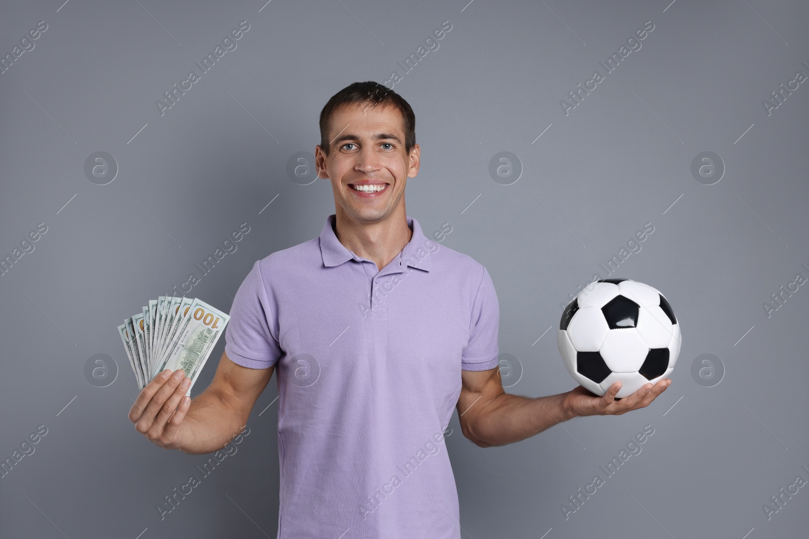 Photo of Man with money and soccer ball on grey background