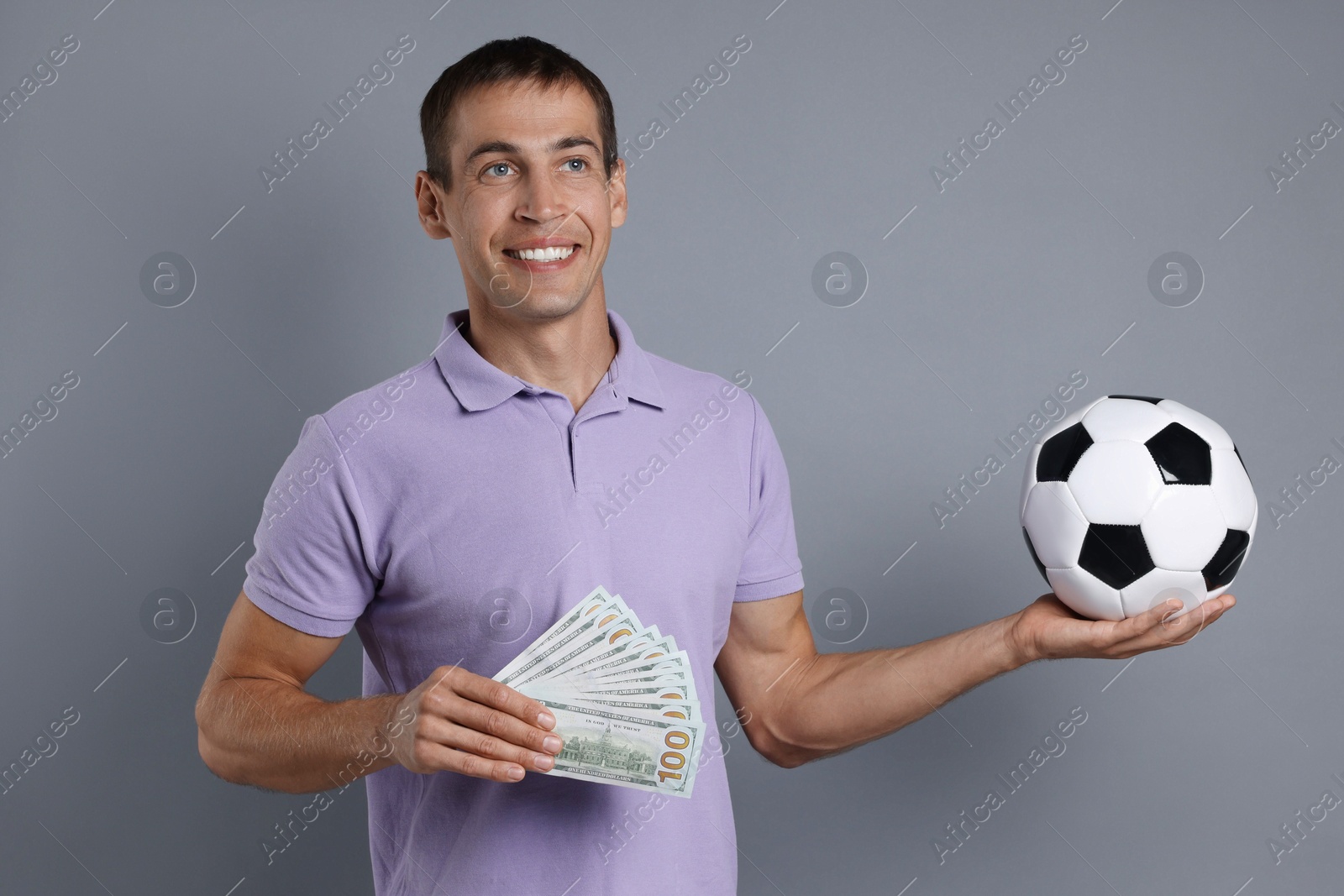 Photo of Man with money and soccer ball on grey background