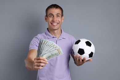 Photo of Man with money and soccer ball on grey background