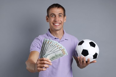 Photo of Man with money and soccer ball on grey background