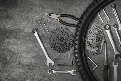 Photo of Parts of bicycle and tools on grey table, flat lay. Space for text