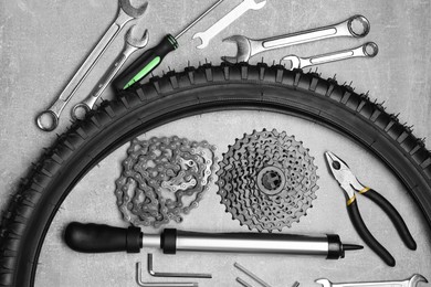 Parts of bicycle and tools on light grey table, flat lay