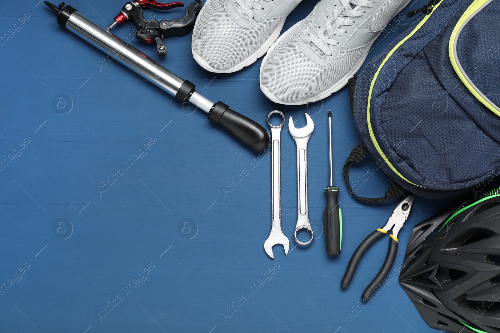 Photo of Bicycle accessories and tools on blue wooden background, flat lay. Space for text