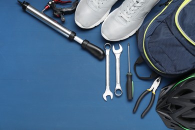 Photo of Bicycle accessories and tools on blue wooden background, flat lay. Space for text