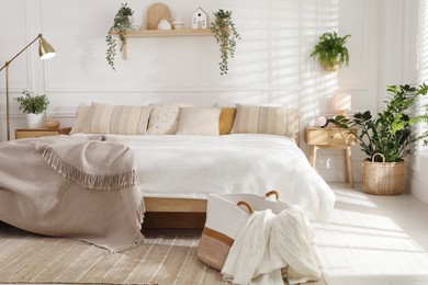 Photo of Stylish bedroom interior with large bed, houseplants and decorative elements