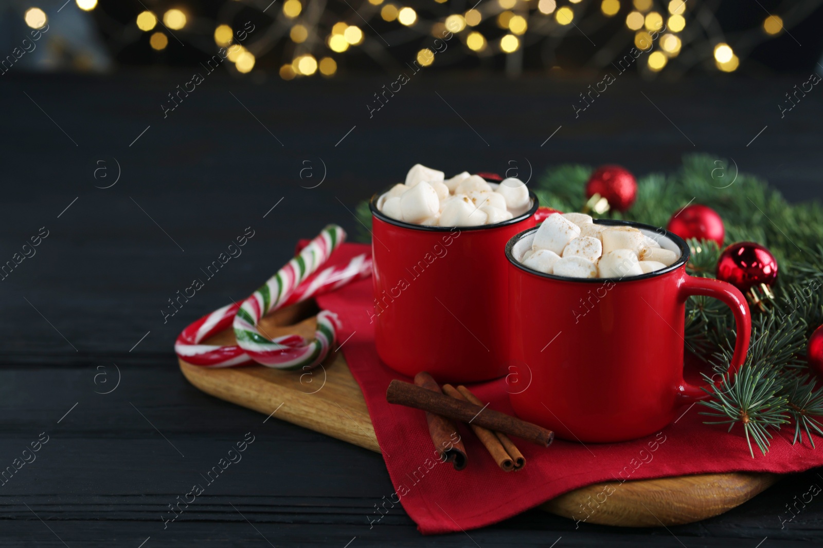 Photo of Tasty hot cocoa drinks with marshmallows in cups on black wooden table, closeup. Space for text