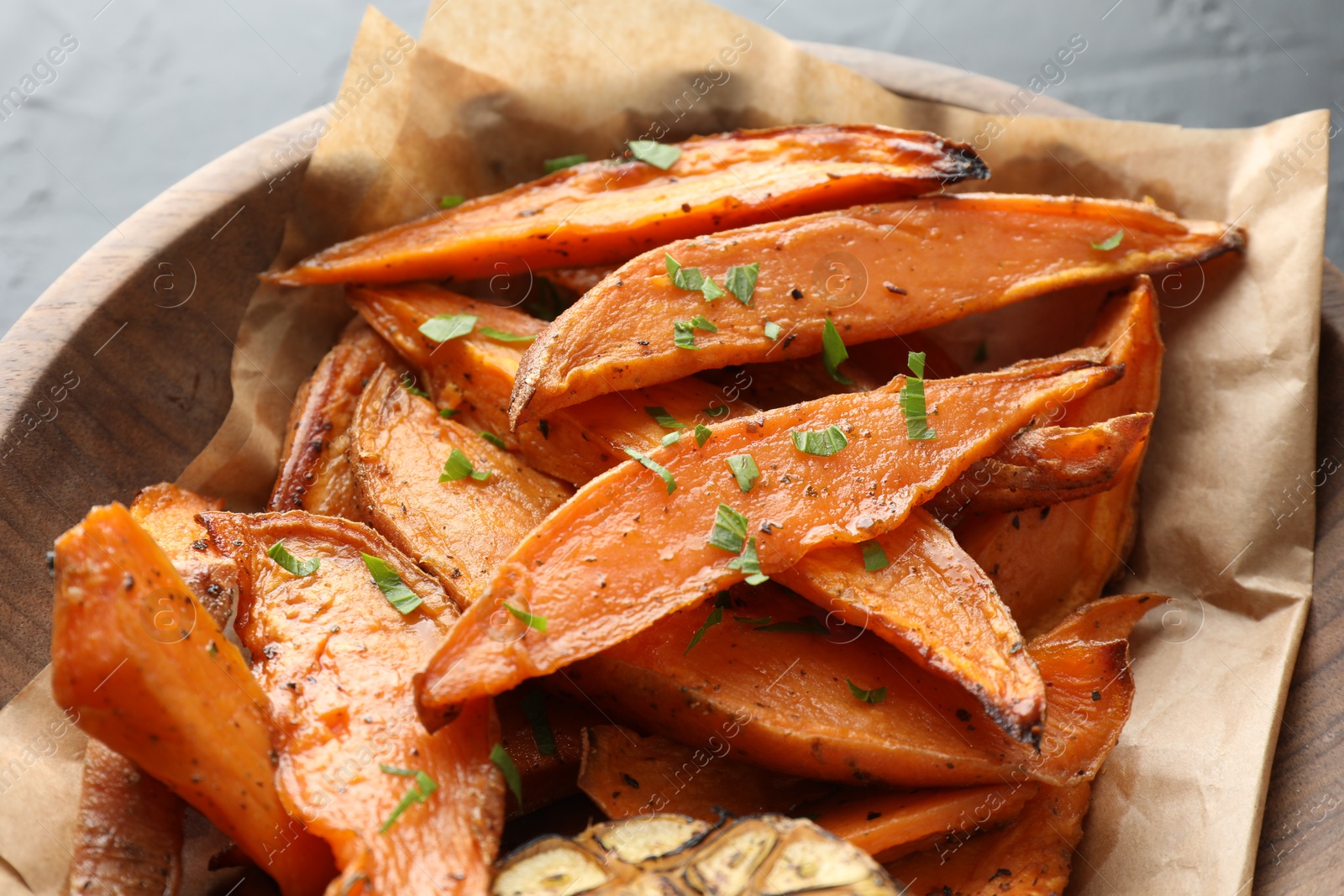 Photo of Tasty cooked sweet potatoes with parsley on table, closeup