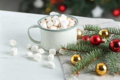 Photo of Tasty hot cocoa drink with marshmallows in mug and Christmas decor on white table, closeup