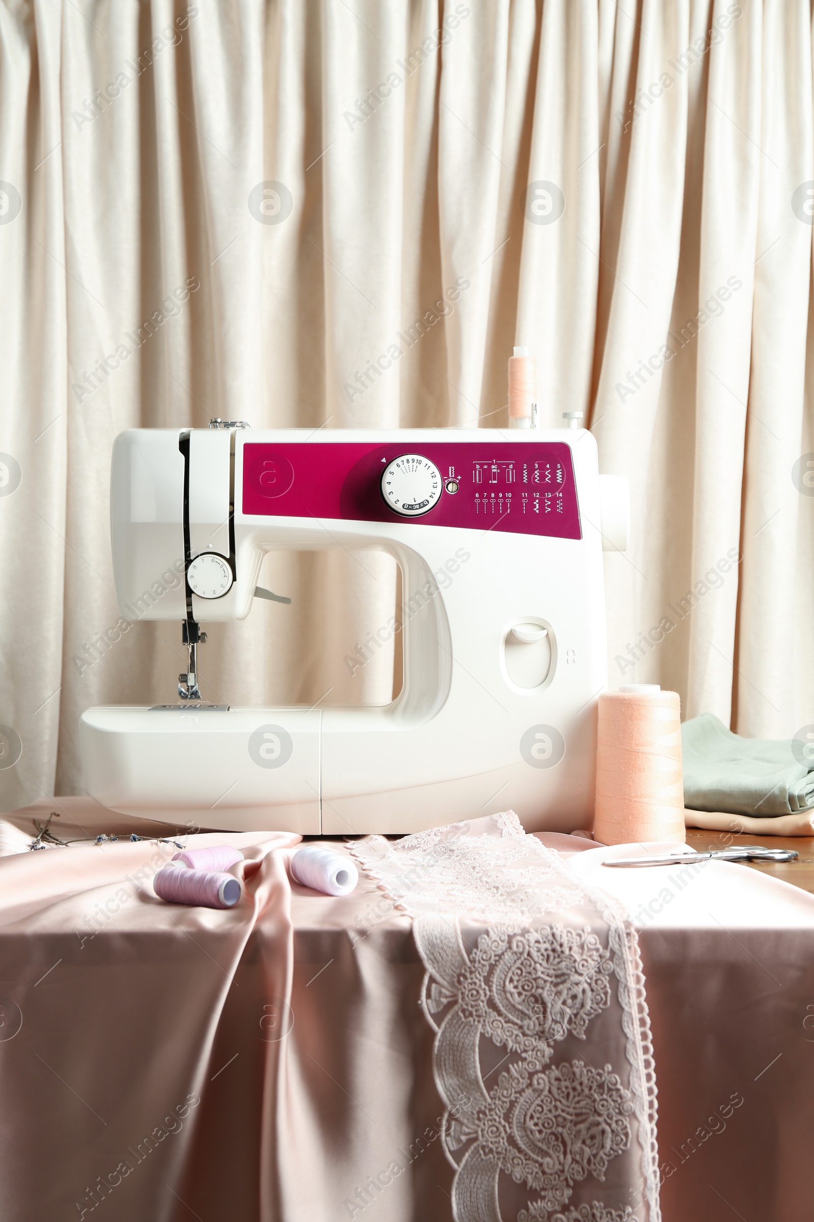 Photo of Sewing machine with fabric and tools on chest of drawers indoors