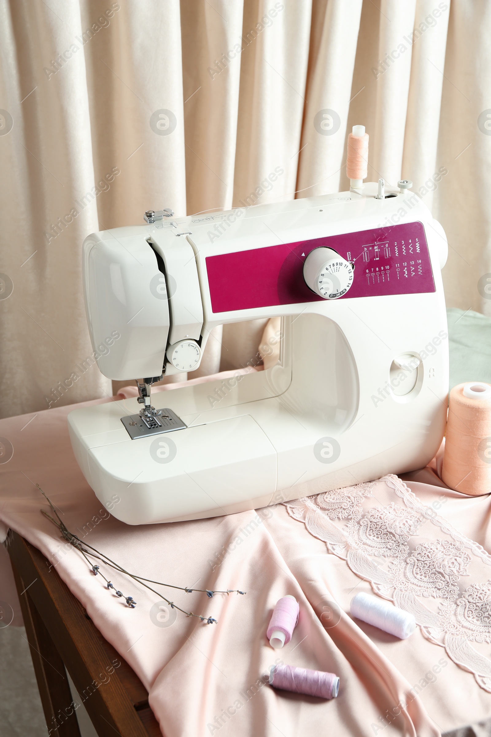 Photo of Sewing machine with fabric and tools on table indoors