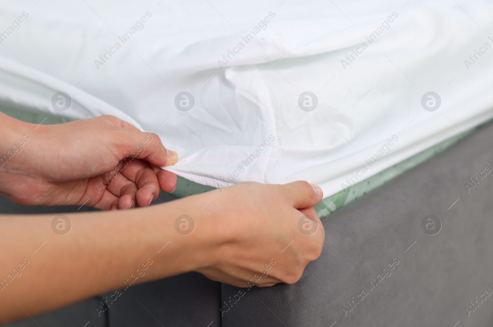 Photo of Woman changing clean bed linens at home, closeup