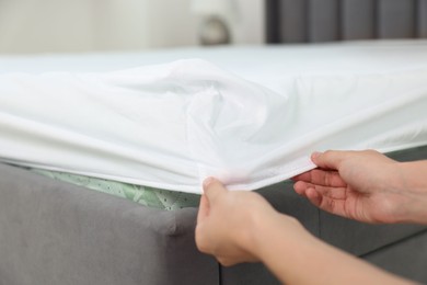 Photo of Woman changing clean bed linens at home, closeup