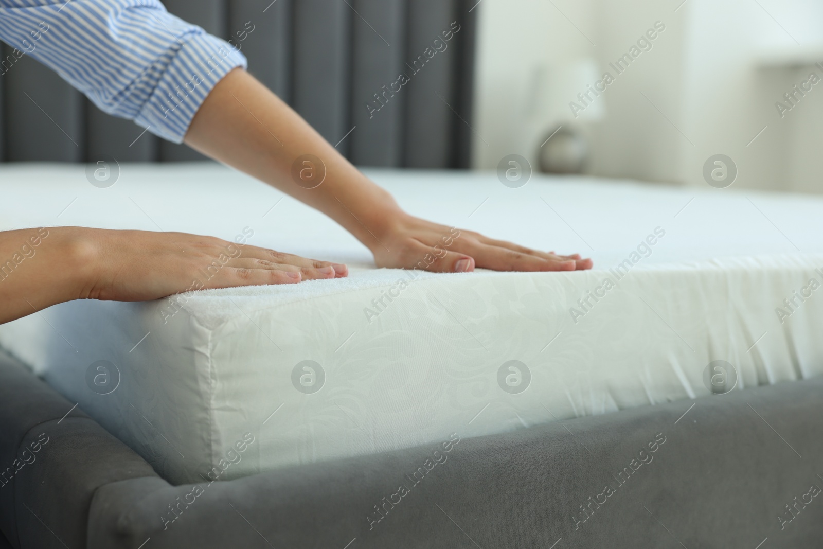 Photo of Woman changing clean bed linens at home, closeup