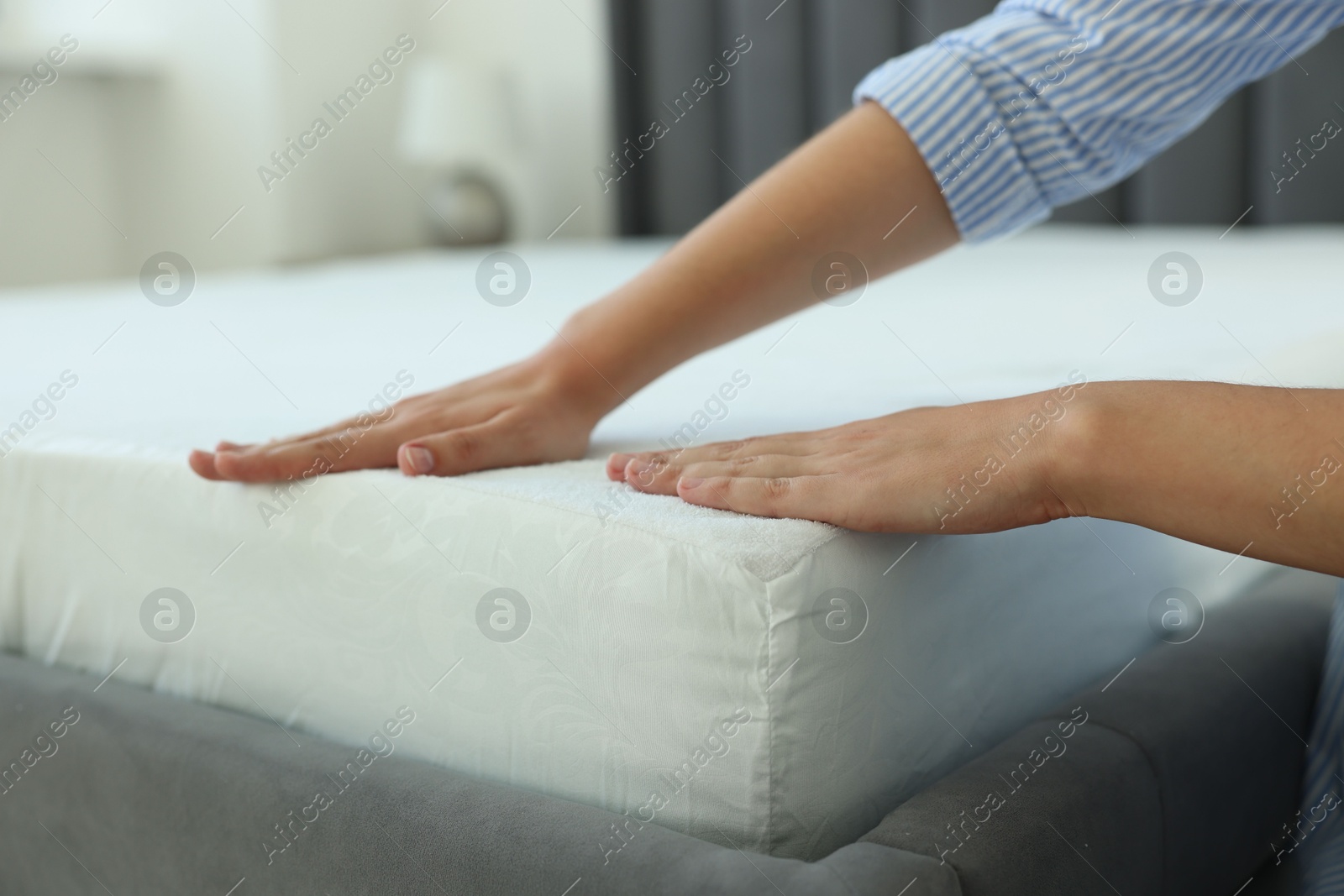 Photo of Woman changing clean bed linens at home, closeup