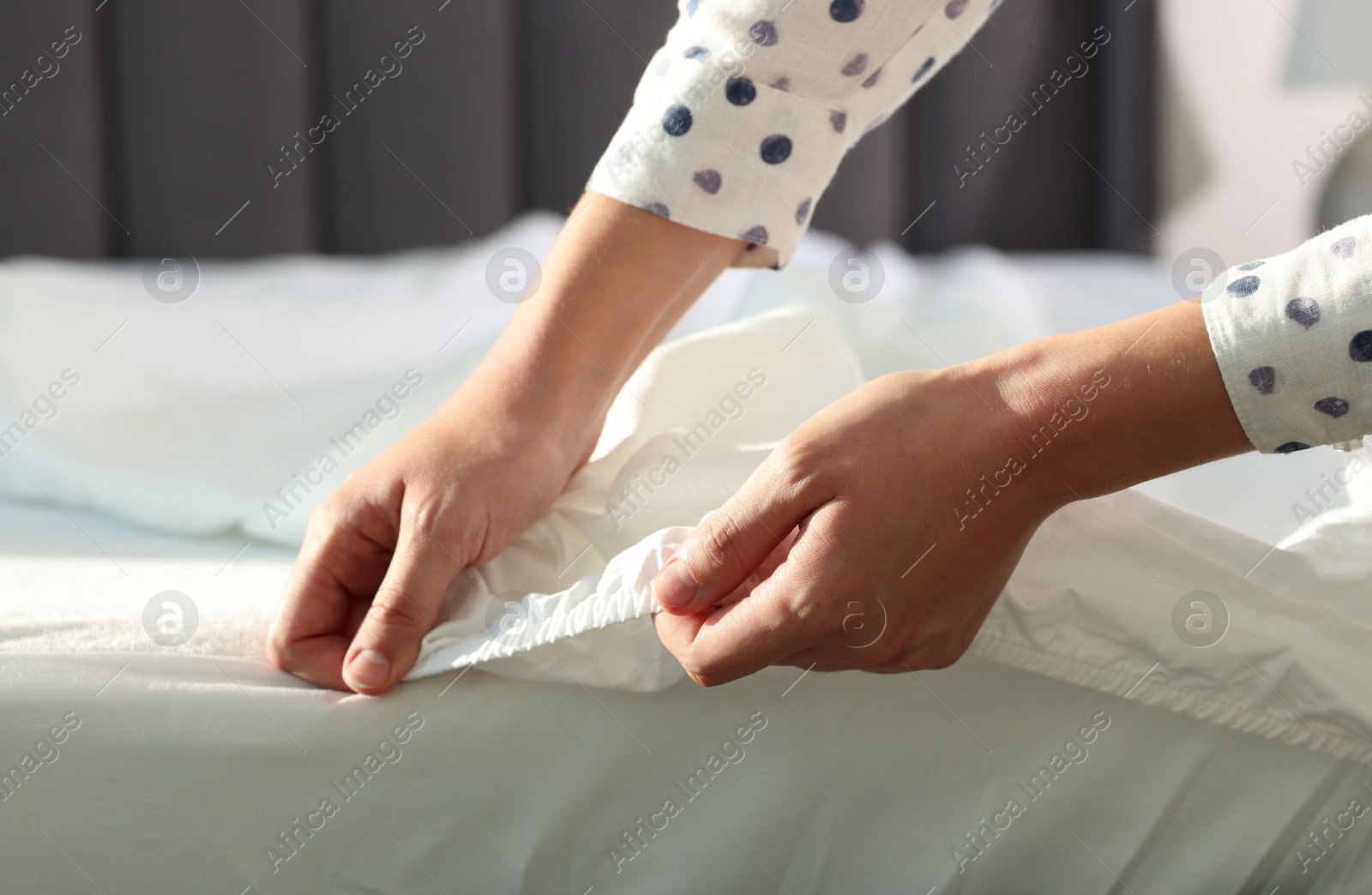 Photo of Woman changing clean bed linens at home, closeup