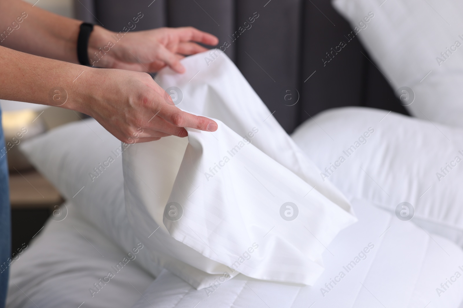 Photo of Woman changing clean bed linens at home, closeup