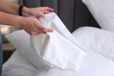 Photo of Woman changing clean bed linens at home, closeup