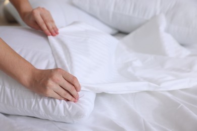 Woman changing clean bed linens at home, closeup