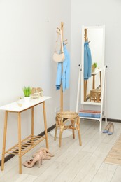 Photo of Clothing rack, mirror, storage bench and clothes in hallway