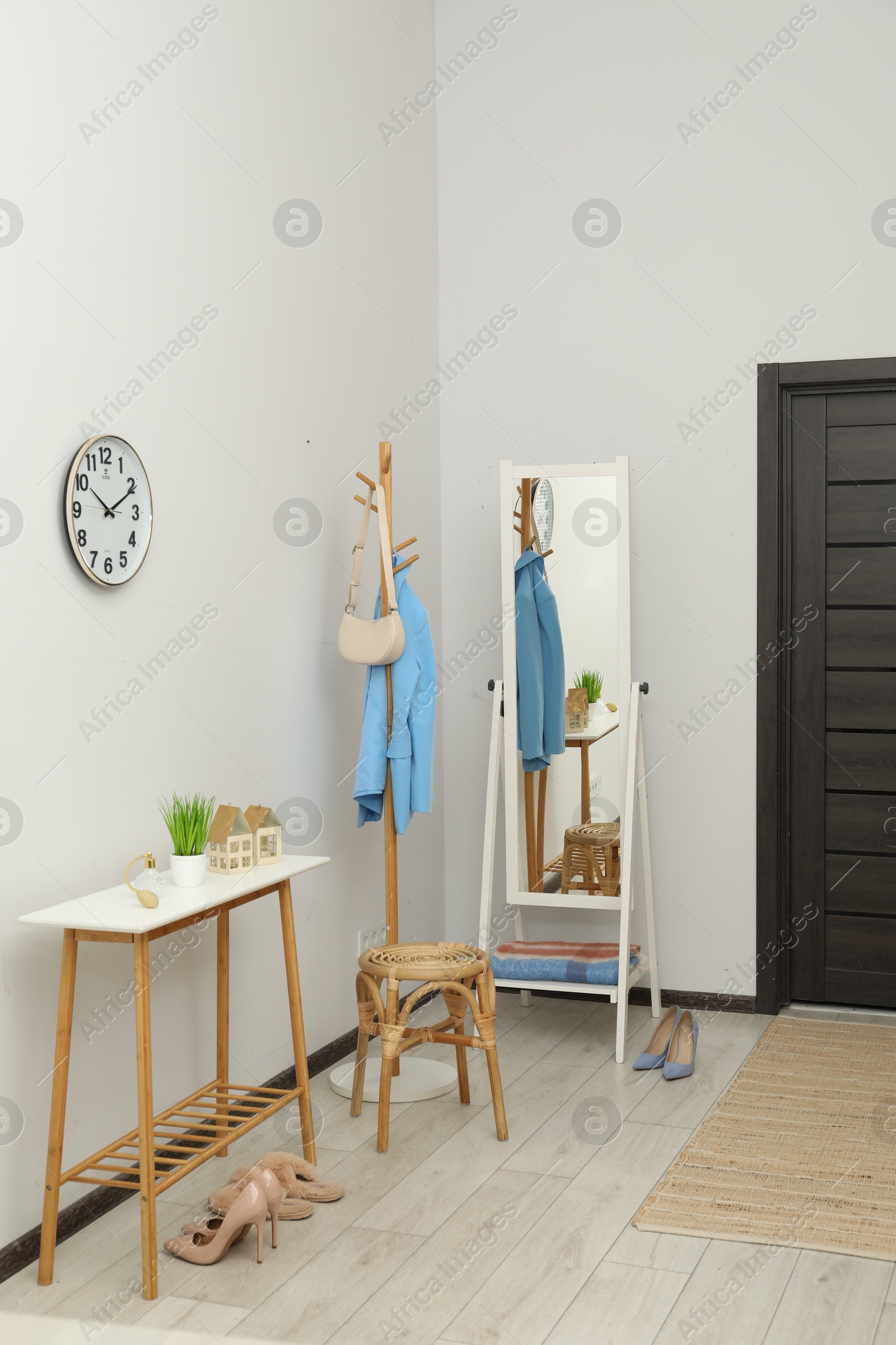 Photo of Clothing rack, mirror, storage bench and clothes in hallway