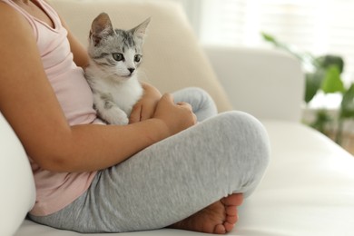 Little girl with cute kitten at home, closeup