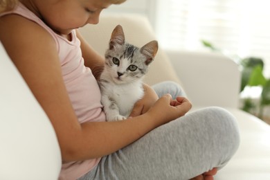 Photo of Little girl with cute kitten at home, closeup