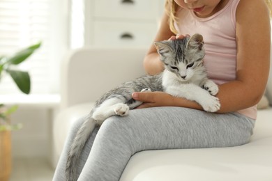 Little girl with cute kitten at home, closeup