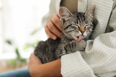 Photo of Woman with cute kitten at home, closeup