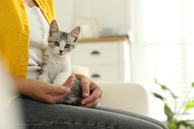 Woman with cute kitten at home, closeup. Space for text